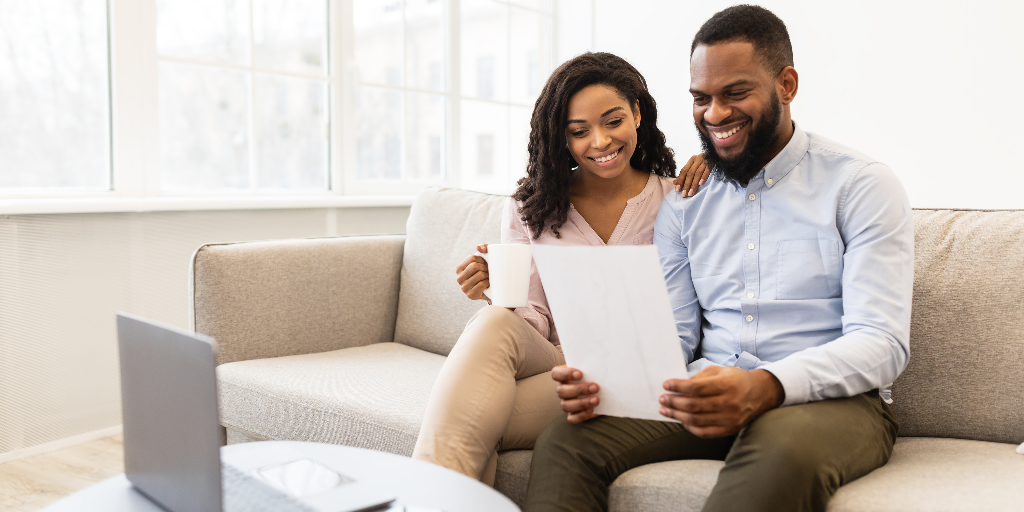  cheerful couple sitting on the couch reading life insurance terms