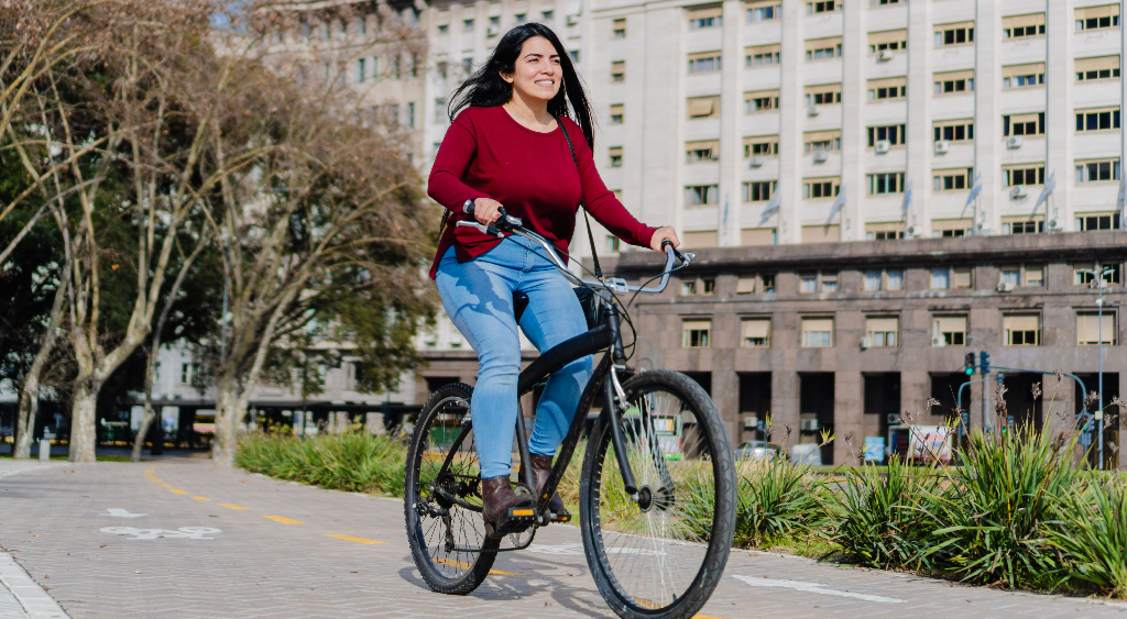 Happy Latina woman biking through her upscale neighborhood