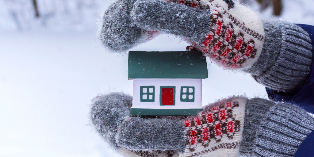 Home in cozy gloved hands during winter, holiday season.